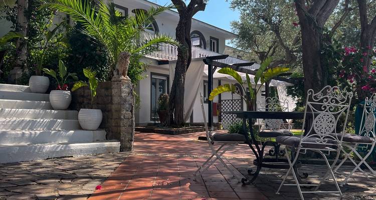 Cour avec sièges extérieurs entourée de verdure.