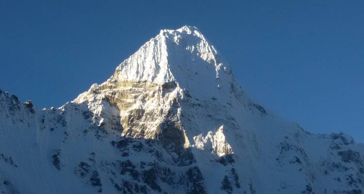 Besneeuwde bergtop onder een strakblauwe hemel.