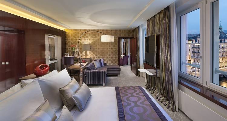 Habitación de hotel lujosa con decoración elegante y ventanas grandes.