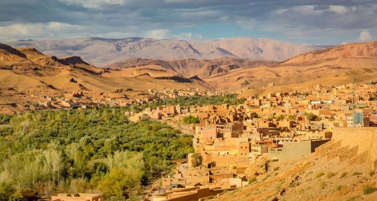 Ouarzazate dorp met groene velden en bergen op de achtergrond.