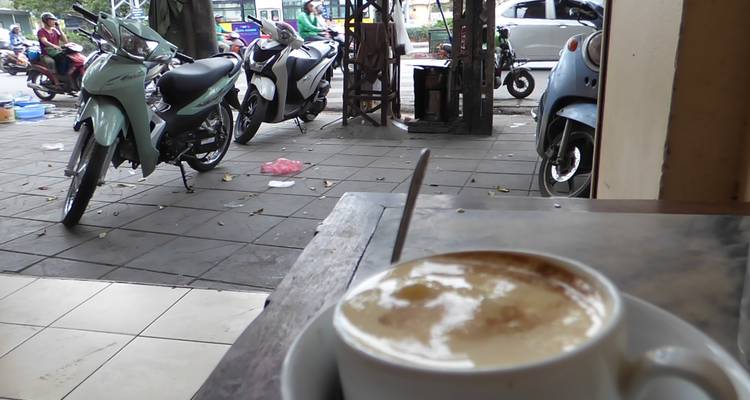 Motorcycles parked on a street with a cup of coffee in the foreground.