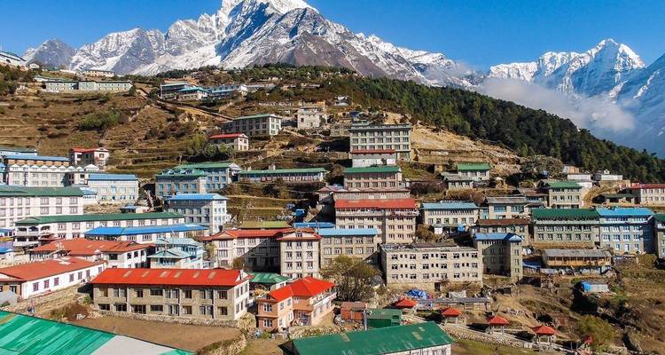 Colorful buildings in a hilly village set against snowy mountain peaks.