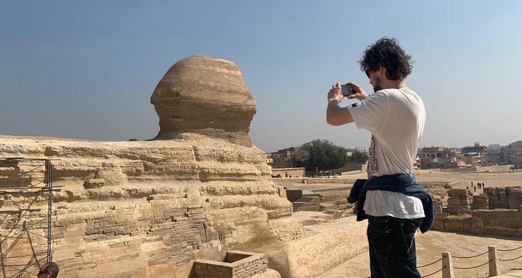 Traveller photographing the Great Sphinx of Giza under a clear desert sky