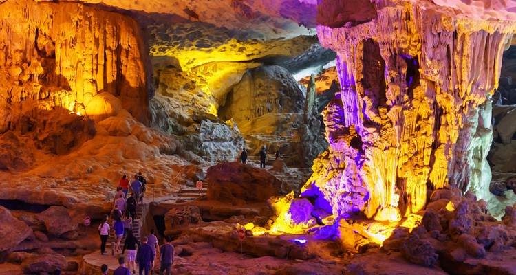 Turistas explorando una cueva brillantemente iluminada con formaciones impresionantes.