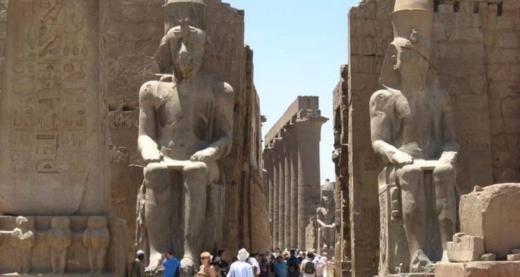Tourists walking between giant ancient statues.