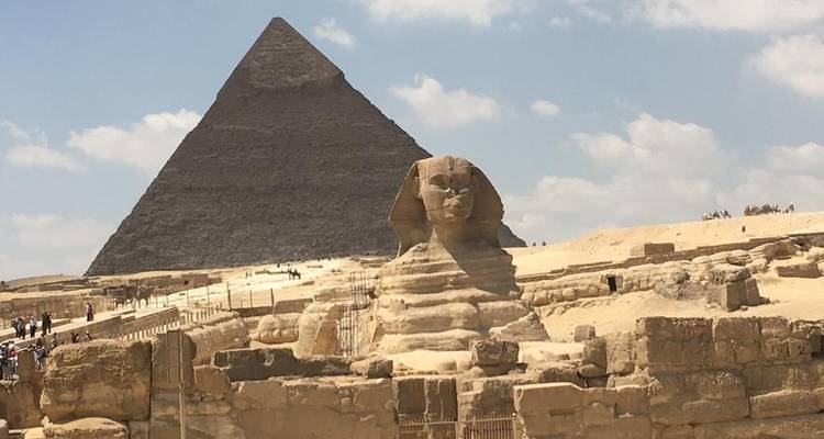 The Sphinx and a pyramid under a clear blue sky.
