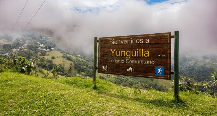 Willkommensschild nach Yunguilla mit bewölkter Landschaft.