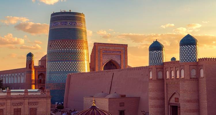 Zonsondergang uitzicht op de Kalta Minor Minaret van Khiva en oude stadsmuren die gloeien in warm licht.