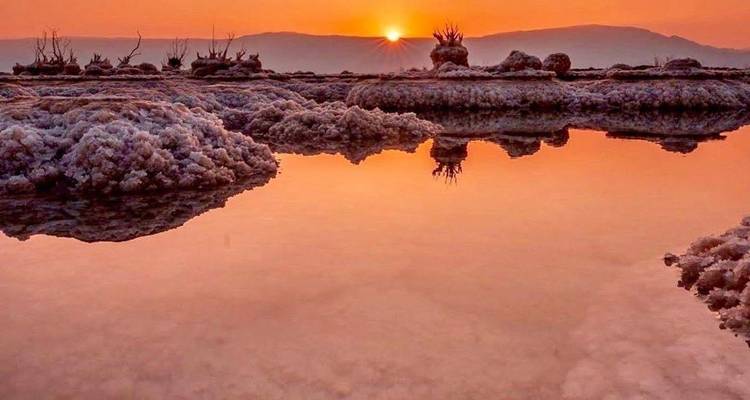 Atardecer sobre el Mar Muerto con reflejos en el agua y formaciones de sal.