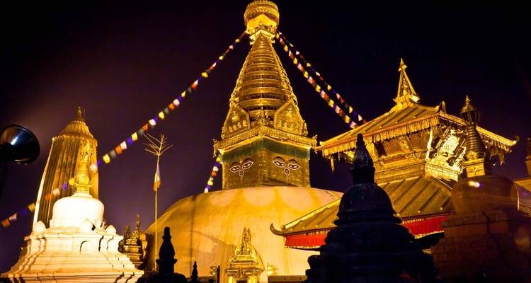 Eine große Stupa und Tempel, die nachts beleuchtet sind.
