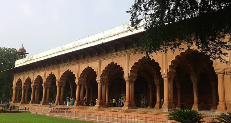 Edificio histórico con múltiples arcos y personas caminando en el parque.