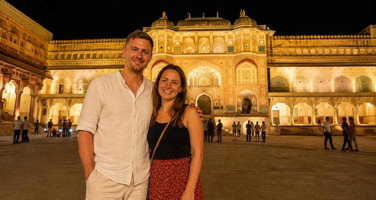 Stel dat in de voorbinnenplaats van het Amber Fort staat, prachtig verlicht 's nachts met bezoekers op een afstand.