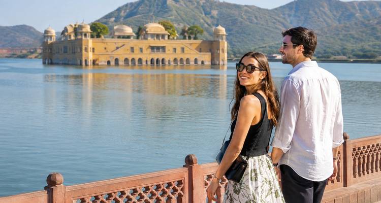 Stel dat loopt langs de reling met panoramisch uitzicht op Jal Mahal en het omringende meer.