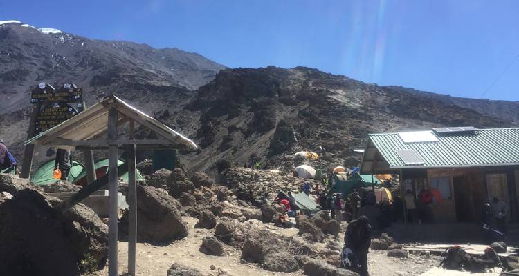 Zone de campement en montagne avec tentes et terrain rocheux.