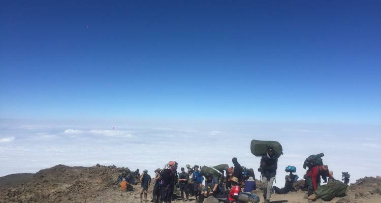 Des randonneurs se reposant sur un plateau de montagne au-dessus des nuages.