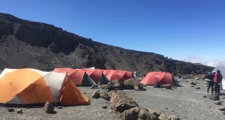 Rangée de tentes sur un paysage montagneux rocheux.