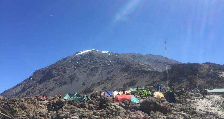 Colorful tents set up on a rocky mountain slope.