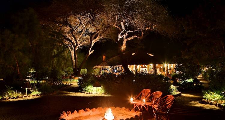Feuerstelle und Sitzbereich in einem Garten bei Nacht.