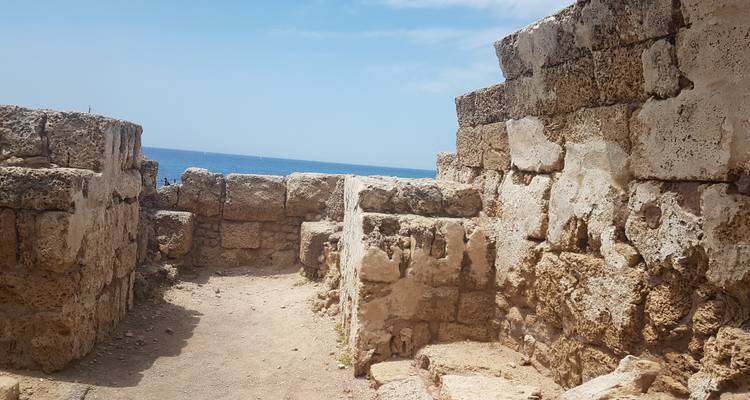 Fortification en pierre surplombant la mer sous un ciel dégagé.