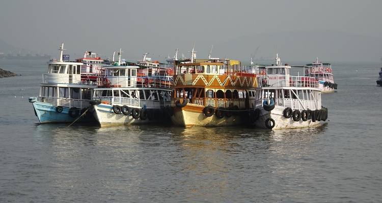 Rangée de petits bateaux colorés sur une mer calme.