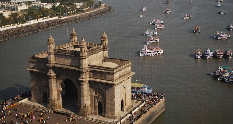 Vue aérienne d'une grande structure de portail en pierre au bord de la mer avec des bateaux.