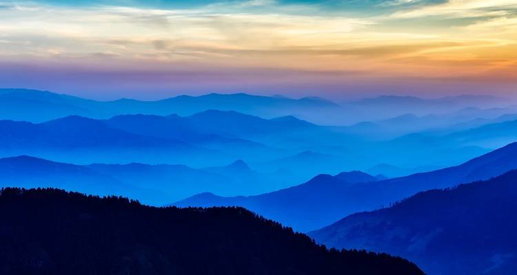 Schichtige Berglandschaft bei Sonnenuntergang mit lebendigen Farben.