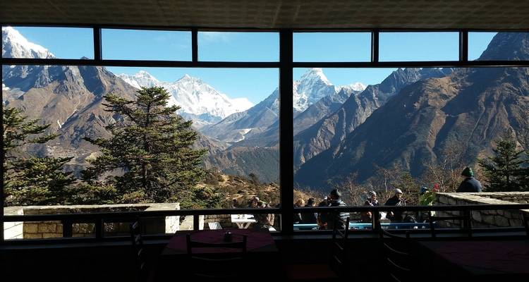 Caféblick mit Menschen, die draußen sitzen, und Bergen im Hintergrund.