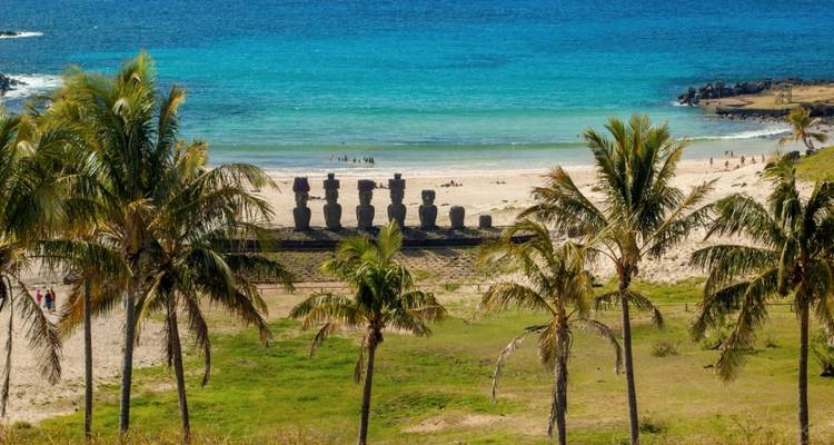 Una playa tropical con palmeras y estatuas Moai.