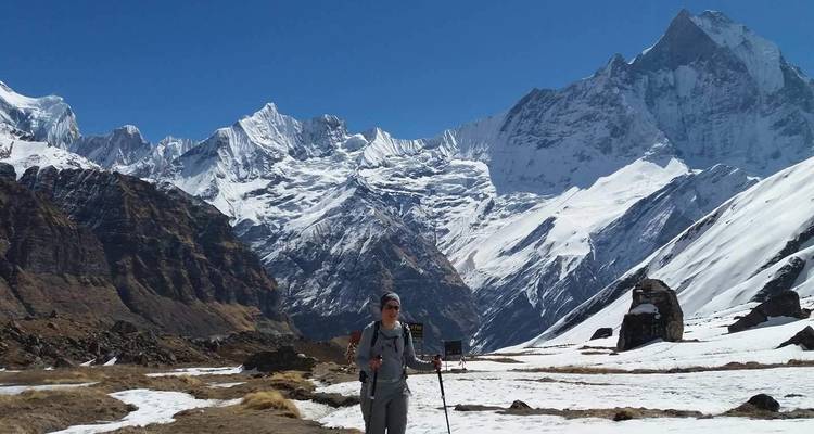 Wanderer mit Trekkingstöcken in einer verschneiten Berglandschaft.