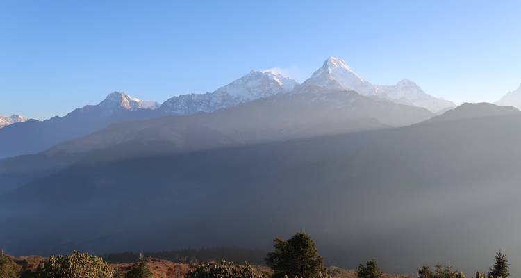 Bergtoppen onder een heldere hemel met mist in de dalen.