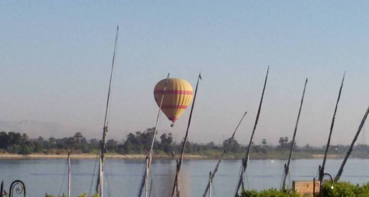 Un globo aerostático solitario asciende sobre el río Nilo en la bruma de la madrugada.