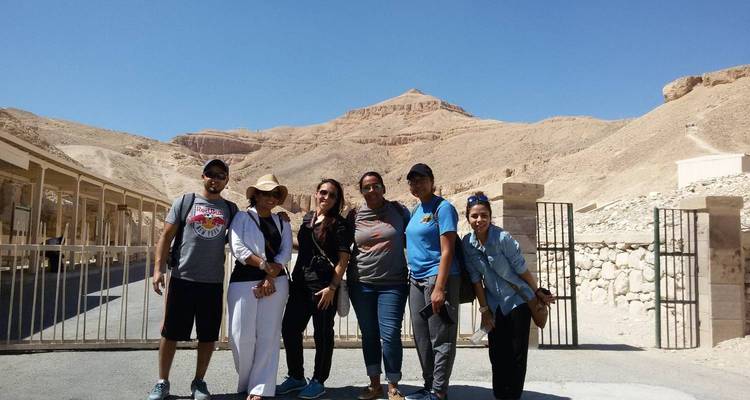 Un grupo de viajeros posa con las escarpadas colinas del desierto del Valle de los Reyes de fondo.