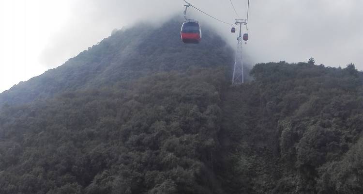 Seilbahn, die einen nebligen Berghang hinauffährt.