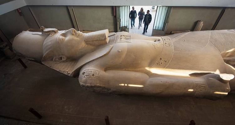 Bezoekers naast een gigantisch liggend standbeeld