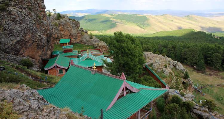 Kloster mit grünen Dächern an einem Berghang mit Blick ins Tal.
