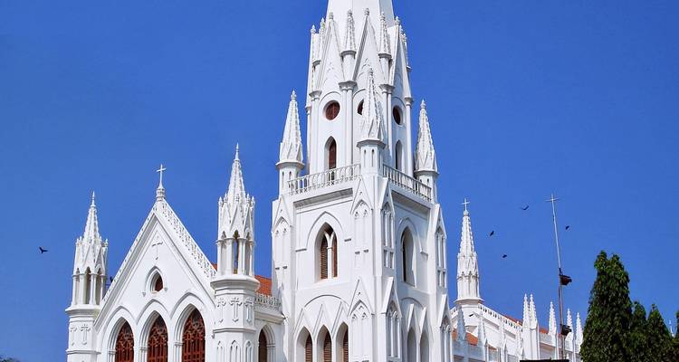 Eine weiße Kirche im gotischen Stil mit hohen Türmen und einem klaren blauen Himmel.