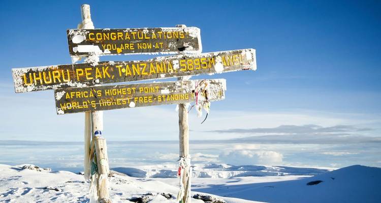 Summit sign at Uhuru Peak with snow-covered surroundings.