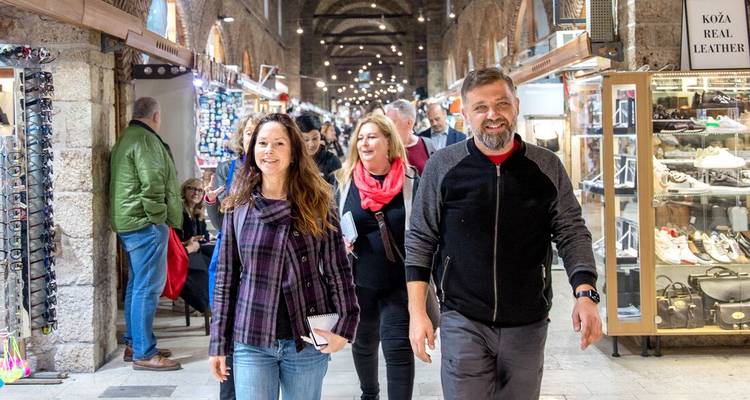 Les voyageurs parcourent un bazar couvert animé bordé de boutiques de maroquinerie et de souvenirs.