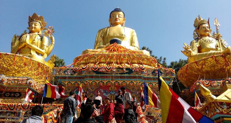 Große goldene Statuen mit Besuchern und Flaggen im Vordergrund.