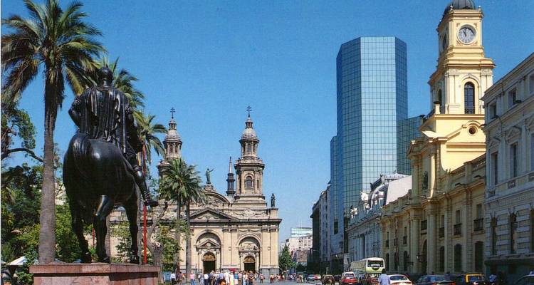 Sunny street scene in front of Santiago’s cathedral with palm trees, equestrian statue and modern tower.