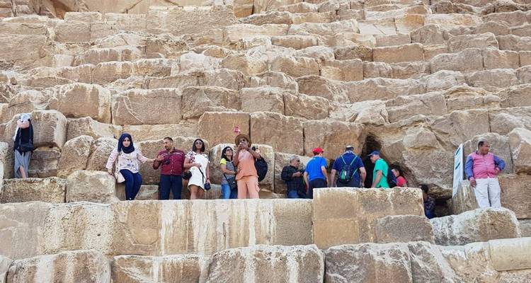 Besucher, die auf den verwitterten Steinblöcken der Großen Pyramide klettern
