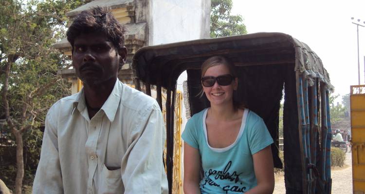 Un turista se sienta en un ciclo-rickshaw al lado del conductor local en un camino polvoriento de Nepal.