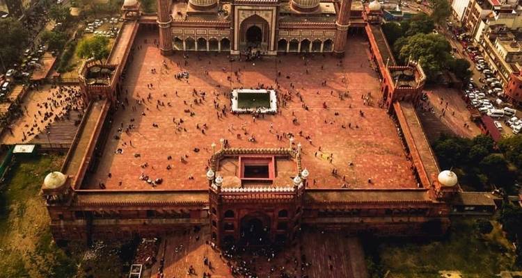 Aerial view of a large mosque courtyard with many people.