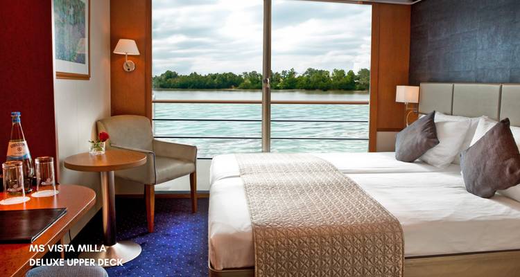 Das Kabineninnere eines Flusskreuzfahrtschiffs mit einem großen Fenster, das den Fluss draußen zeigt.