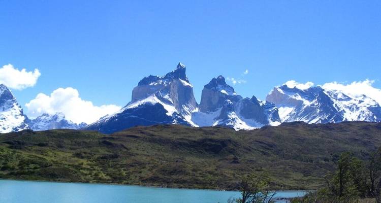 Montañas cubiertas de nieve bajo un cielo azul despejado con un lago en primer plano.