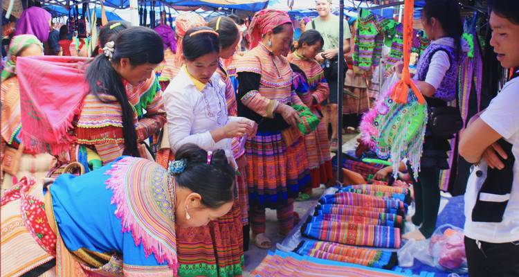 Bunte Marktszene mit Einheimischen, die traditionelle Stoffe begutachten.
