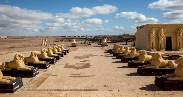 Binnenplaats met standbeelden en grote structuren onder een gedeeltelijk bewolkte hemel.