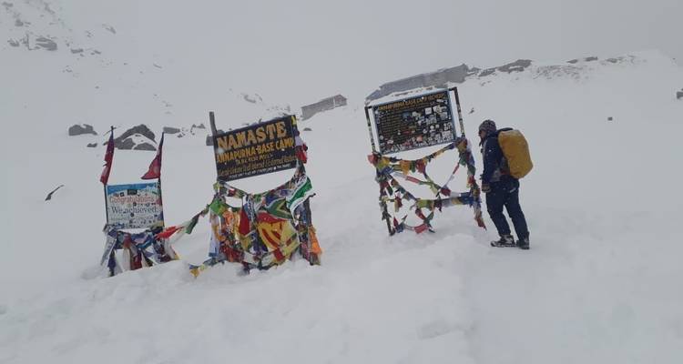 Person, die neben bunten Gebetsfahnen und Schildern in einem schneebedeckten Gebiet steht.