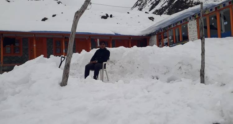 Person, die auf einem Stuhl vor einem schneebedeckten Gebäude sitzt.