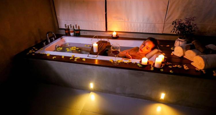 Person, die in einer luxuriösen Umgebung mit Kerzen badet.